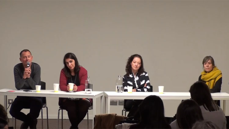 Four panelists sit at a table taking questions from the audience.