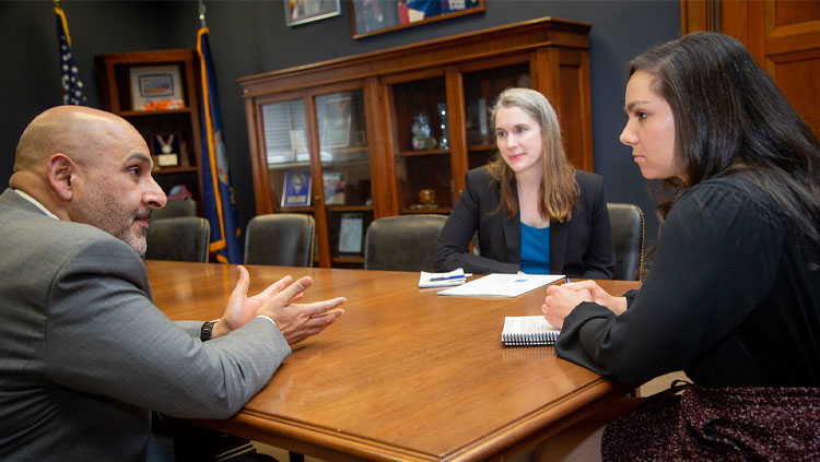 Three people sit around a table discussing science advocacy.