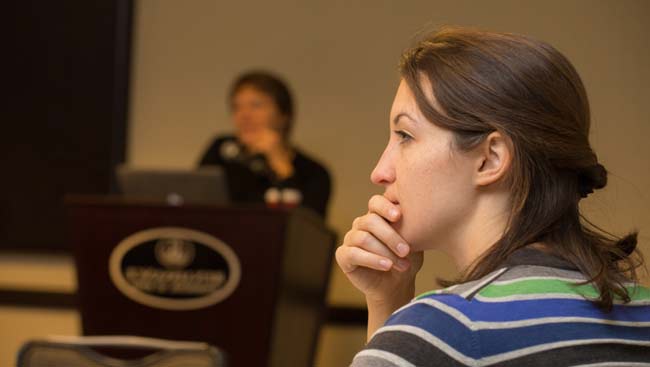 A female listens intently to a presentation. 