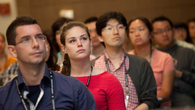 Seated University Students Attentively Listening to a Lecture - Focus is on Woman