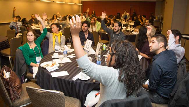 Room of Seated Men and Women Raising their Hands at an Event