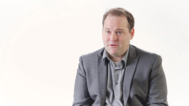 Kip Ludwig speaking in front of a white background