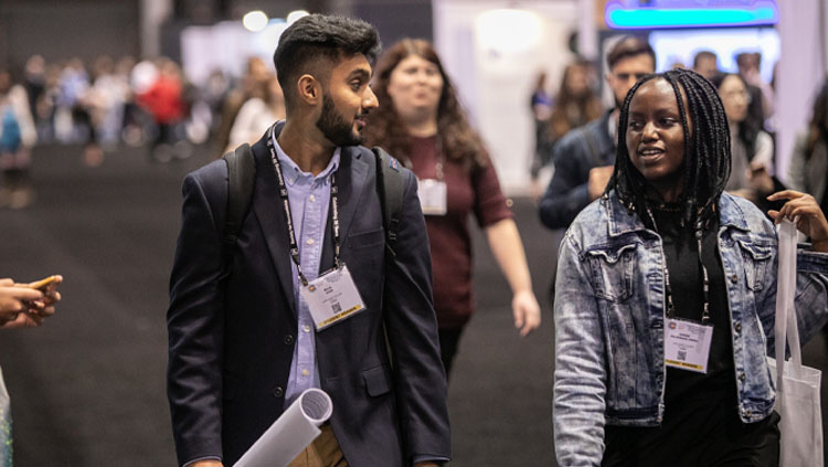 Image of two young adults talking while walking through the poster floor at Neuroscience 2019.