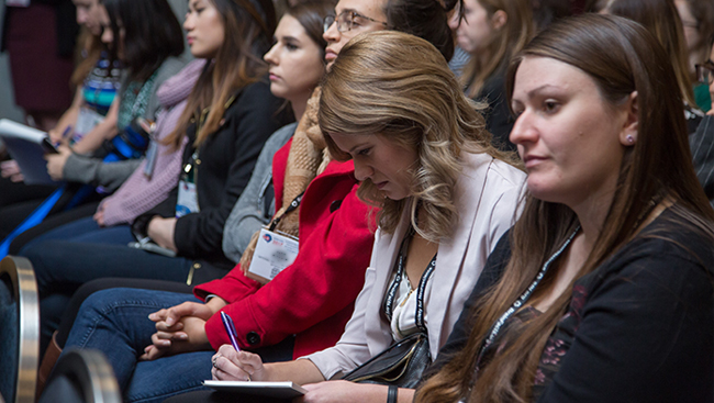Neuroscience meeting attendee taking notes at a presentation