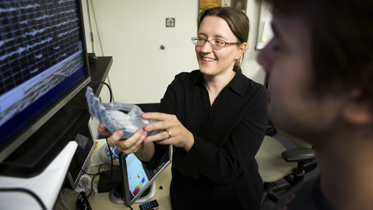 Cynthia Chestek talking to PhD student Zach Irwin about Utah array signals recorded from primary motor cortex, holding the Touch Bionics multi-articulated prosthetic hand.