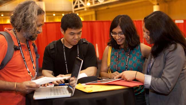 A group of male and female neuroscientists discussing what they're looking at on a tablet.