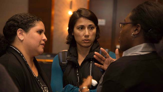 Three female faculty talk at a conference. 
