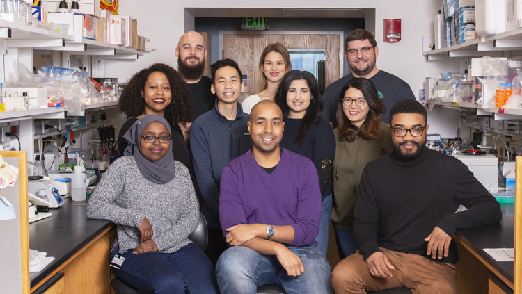 Corey Harwell sitting with nine mentees in a lab