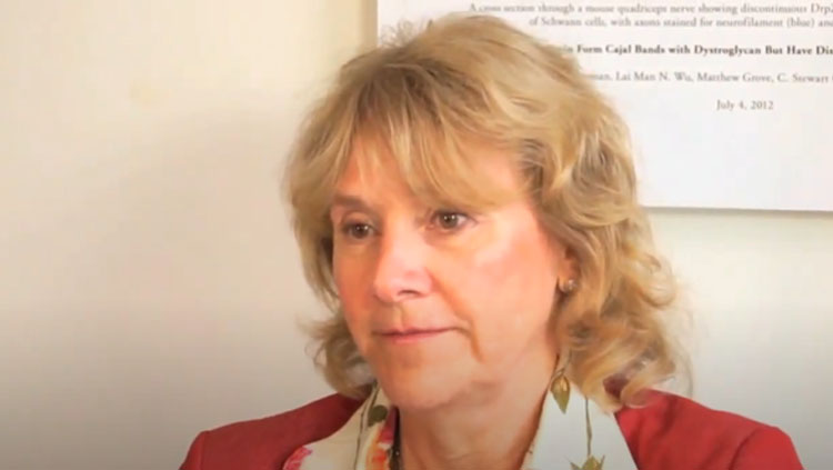 A woman in a red jack talks to a camera.