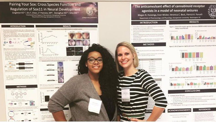 Kaela Singleton and a colleague stand together in front of scientific posters.
