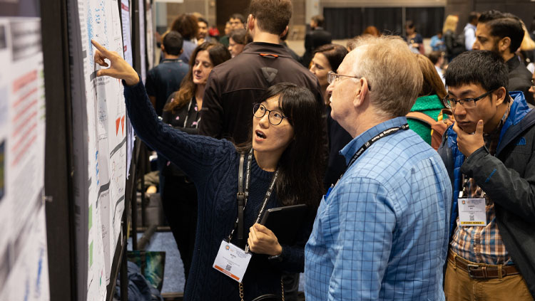 A female Neuroscientist explains her research poster to a man at Neuroscience 2019.