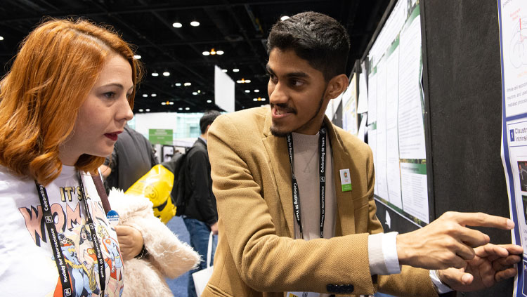 A man explains his research poster to an onlooker at Neuroscience 2019.