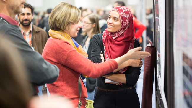 Image of a woman explaining her poster to another woman on the poster floor at Neuroscience 2017