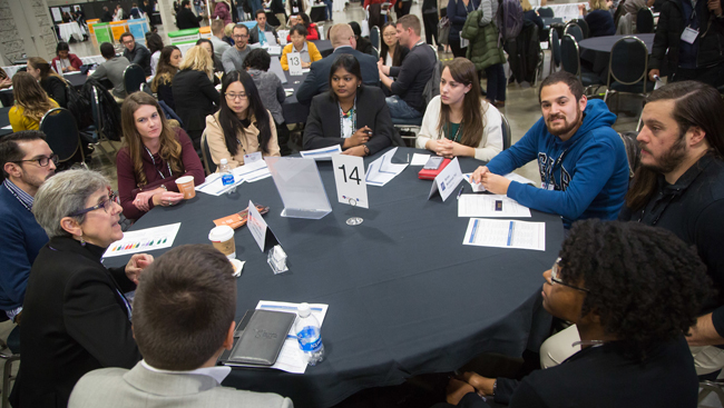 Image of ten people sitting at a table and having a discussion at Neuroscience 2017