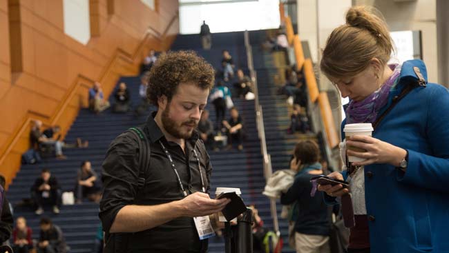 Male and female conference attendees share tweets at the annual meeting. 
