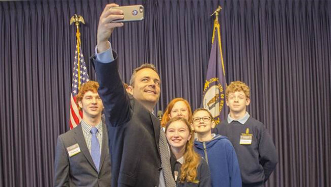 Lawmaker takes photo with a group of students. 