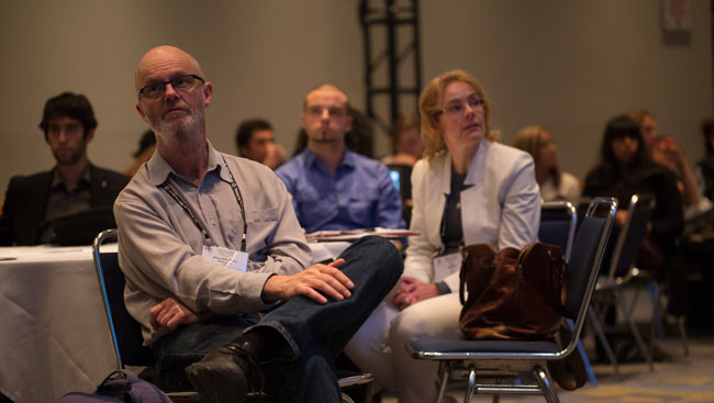 Male neuroscientist listens to a lecture. 