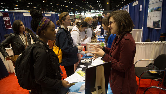 Two female neuroscientists explain their career backgrounds and science at a networking event. 