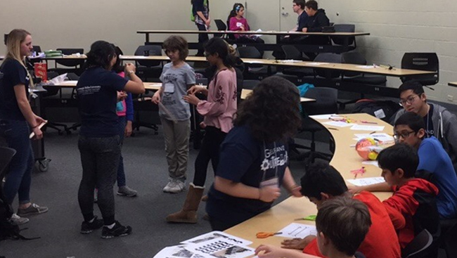 With the help of Carnegie Mellon Nu Rho Psi members, middle school students play partner games and cut out parts of pictures to learn about reflexes and optical illusions.
