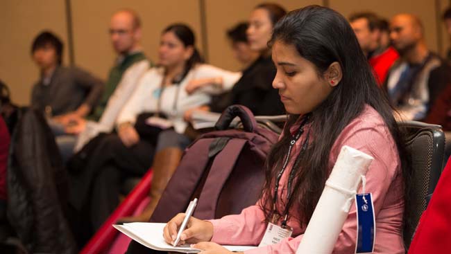 A female neuroscientist takes notes during a talk. 