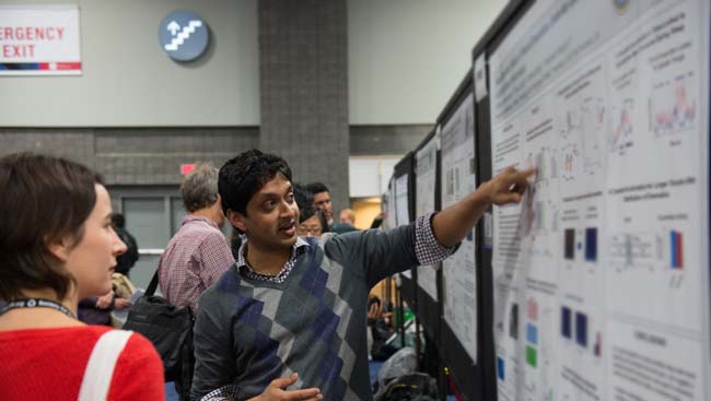 A male neuroscientist shares his science at the SfN annual meeting poster session. 