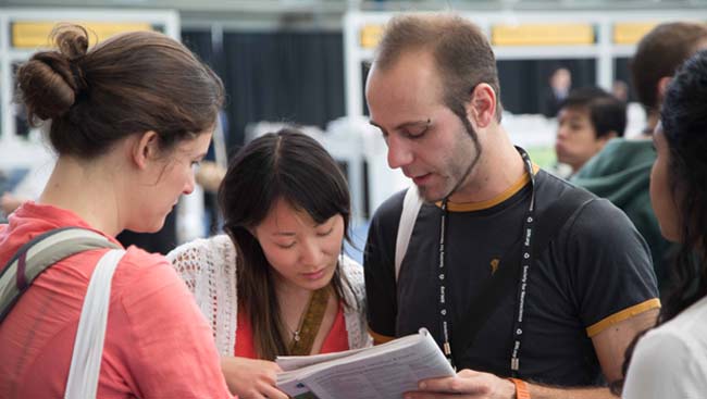 Female and male annual meeting attendees study the conference program.