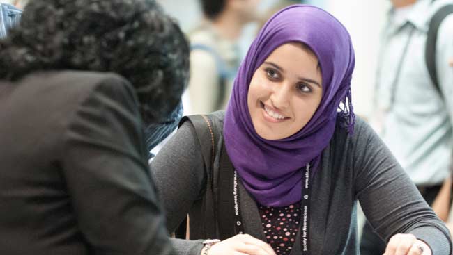 Young woman smiling and talking with another woman at SfN's annual meeting.