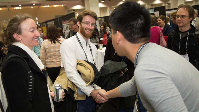 Two men introduce themselves while others look on at SfN's annual meeting.