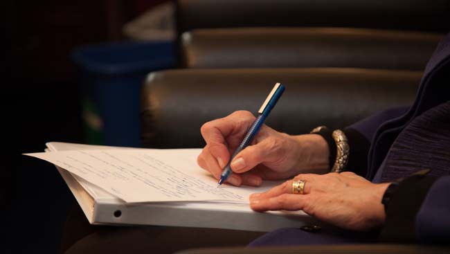 A hand writes notes during a lecture. 