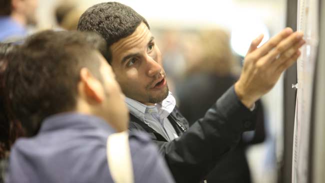 Two men discuss a scientific poster at SfN's annual meeting.