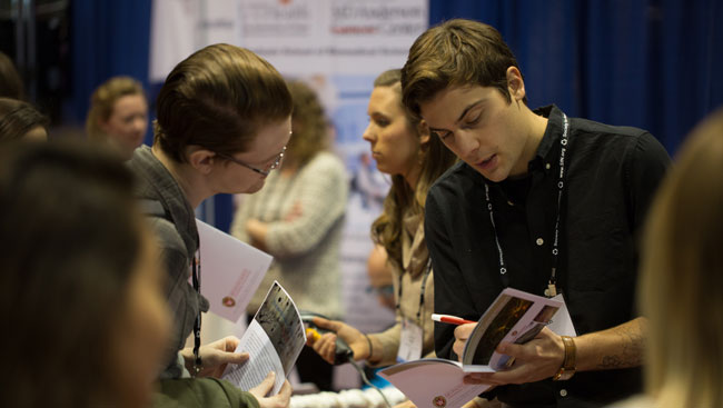 Two annual meeting attendees discuss the items in the event program