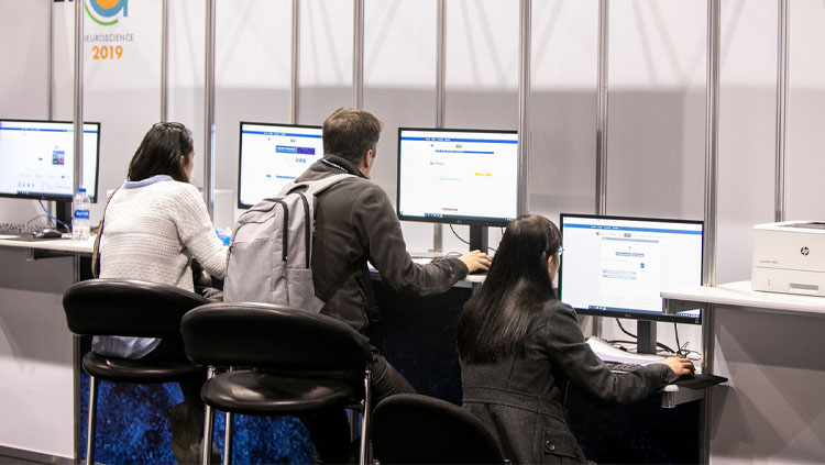 Three young adults look through job postings at the NeuroJobs center at Neuroscience 2019.