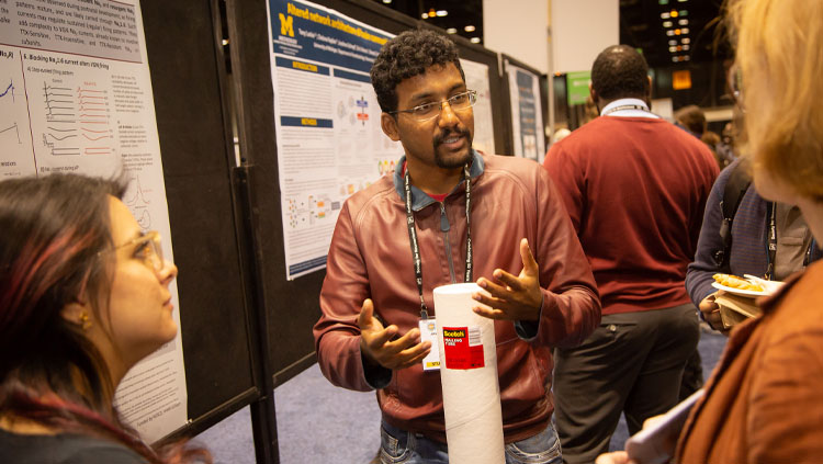 Three neuroscientists discuss a scientific display on the poster floor at Neuroscience 2019