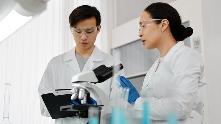 Man and a Woman Wearing Lab Coats and Protective Goggles