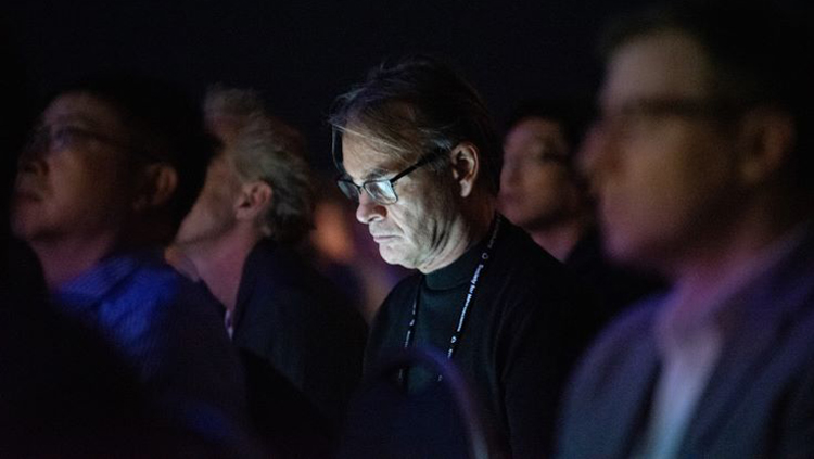 Man looks at his laptop in dark lecture room.