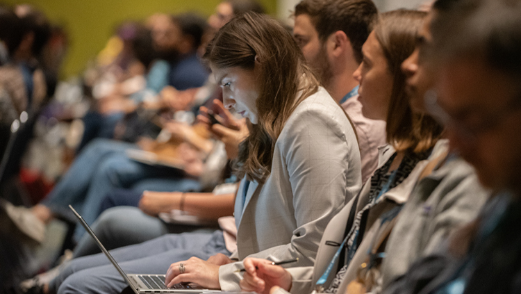 Woman looks at laptop screen in a lecture hall.