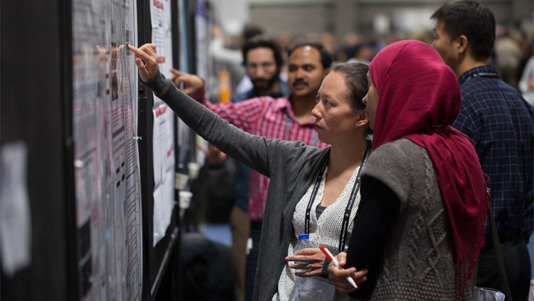 Two women discuss a poster presentation at the Society for Neuroscience annual meeting