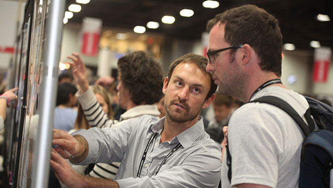 Two male neuroscientists discuss scientific research findings at a conference.  