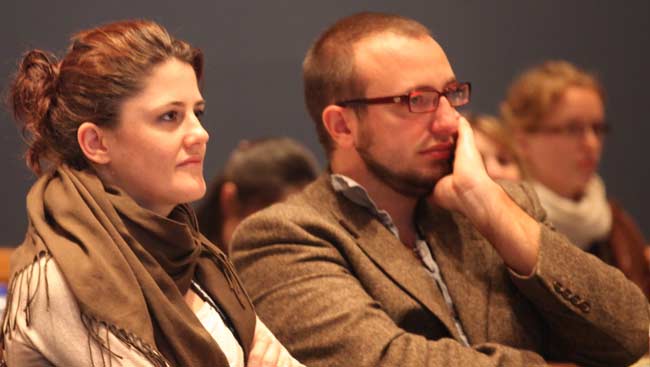 Male and female neuroscientists listening intently at a lecture.