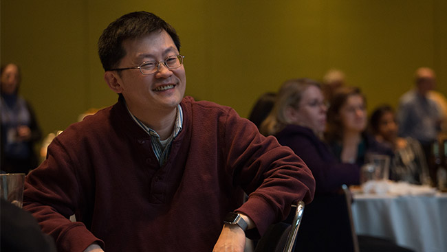 A male neuroscientist listens to a lecture at a conference. 