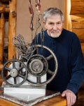 Peter Dallos sits behind one of his sculptures
