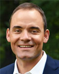 Headshot of Charles Gersbach wearing a white collared shirt and blue jacket.