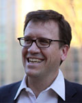 Headshot of Doug Weber wearing a white button up shirt with a black jacket.