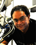 Headshot of Eduardo Rosa Molinar standing next to lab equipment wearing a black collared shirt.