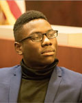Image of Fitzroy Wickham wearing a black turtle neck with a blue jacket and black glasses.