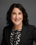 Headshot of Suzanne Rivera wearing a polka dotted shirt with a black jacket.